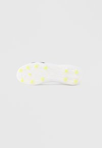 Podeszwa korków piłkarskich wykonana z białej gumy z żółtymi kołkami. Posiada fakturowaną powierzchnię i rowki zapewniające przyczepność. Minimalistyczne oznaczenia w ciemnym kolorze.