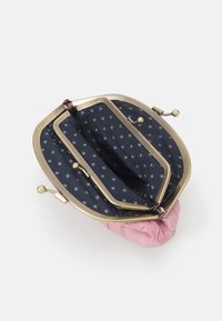 Rosa stoffveske med metallklips, med en marineblå innredning dekorert med hvite stjernesymboler. Åpen visning, som viser to rom.