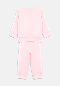 Conjunto de sudadera rosa y pantalones a juego hechos de algodón suave. Cuenta con rayas blancas laterales, puños acanalados y un ajuste relajado.