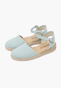 Espadrilles en toile bleu clair avec une bride de cheville, semelle en jute tressé, bout rond et talon plat. Texture douce et design simple.