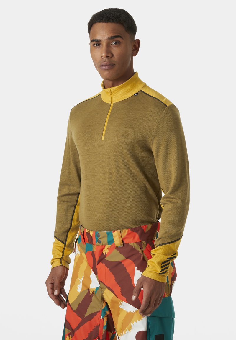 Langsleeve, olijfgroen trui met een gele kraag en rits. Heeft een gestructureerde stof en contrasterende zwarte stiksels op de schouders.