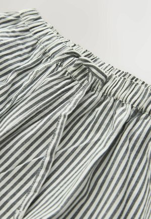 Nahaufnahme des elastischen Bunds mit schwarz-weißen vertikalen Streifen an leichten Shorts oder Hosen aus Stoff.