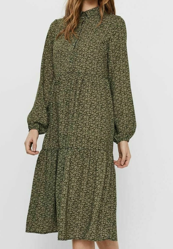 Abito floreale verde con maniche lunghe a sbuffo, colletto con bottoni, vita arricciata e gonna a strati. Realizzato in tessuto leggero.