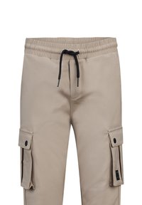 Beige cargobroek met elastische tailleband, zwarte trekkoord, zijzakken en een gladde textuur. Beschikt over een drukknoopsluiting op de zakken.
