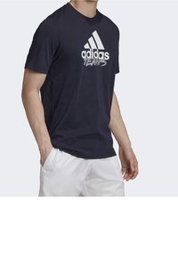 Námořnická modrá tričko s krátkým rukávem s bílým logem "adidas" a textem "TENNIS", vyrobené z měkkého materiálu, s klasickým střihem.