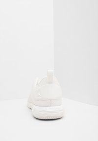 Witte sportieve schoen met een gestructureerde bovenkant, ronde vorm, rubberen zool en een trekkoord aan de hiel. Beschikt over een subtiel logo aan de zijkant.