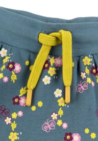 Shorts en tissu bleu avec une taille froncée, agrémentés d'un cordon jaune et d'un imprimé floral en rose, blanc et violet.