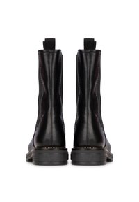 Botines de cuero negro hasta el tobillo con paneles laterales elásticos, un acabado suave y una suela de goma negra texturizada. Presentan una lengüeta en la parte posterior.