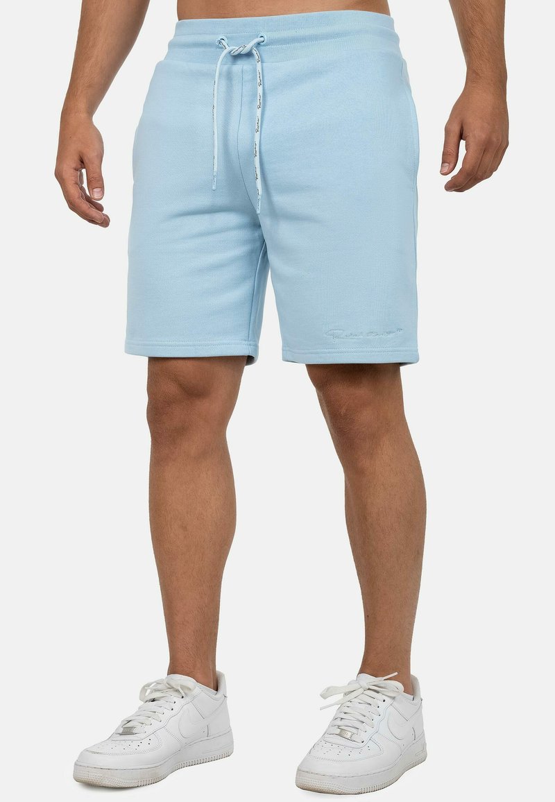 Shorts bleu clair en tissu texturé avec une taille élastique et un cordon de serrage ; comprend un logo en relief sur l'ourlet avant.
