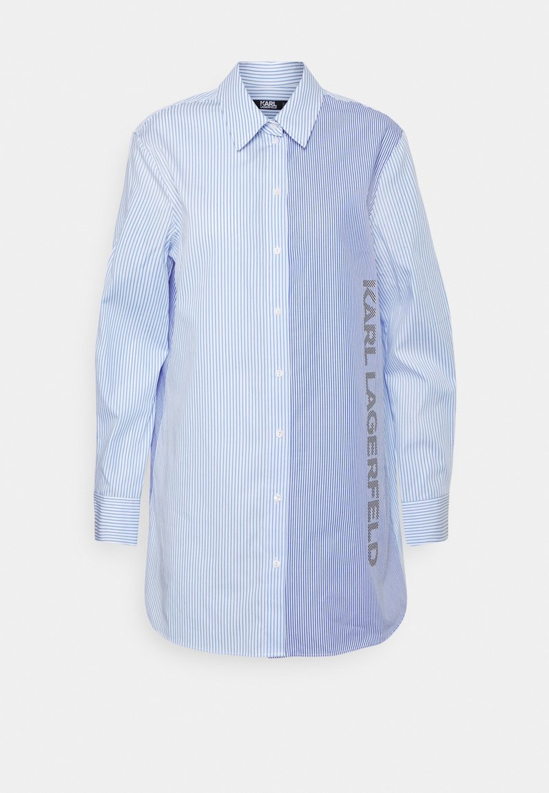 Chemise à manches longues boutonnée avec des rayures verticales bleues et blanches, comportant le texte "KARL LAGERFELD" imprimé verticalement sur le côté droit.