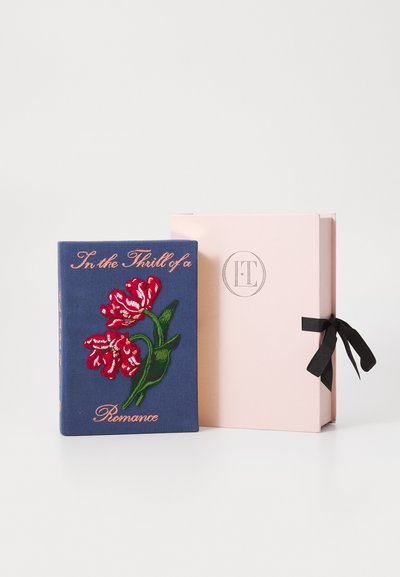 Copertina di libro in tessuto blu con fiori rossi e il testo "Nel Brivido di un Romance" accanto a una scatola rosa pallido legata con un nastro nero.