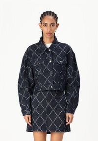 Donker denim cropped jack met een diamanten kettingpatroon, voorzien van twee borstzakken, knoopsluiting en gecombineerd met een bijpassende rok.