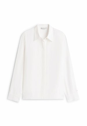 Chemise blanche à manches longues avec un col pointu, boutons avant cachés et poignets, présentée à plat sur un fond blanc.