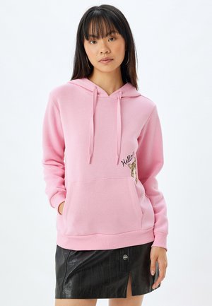 Lichtroze hoodie met een voorzak, koordjes en geborduurde "Hallo" tekst naast een luipaardontwerp. Geribbelde boorden en zoom.