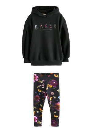 Czarna bluza z kapturem z wielokolorowym napisem "BAKER by Ted Baker" w połączeniu z czarnymi legginsami z wyrazistymi, kwiecistymi wzorami w kolorach fioletowym, żółtym i różowym.