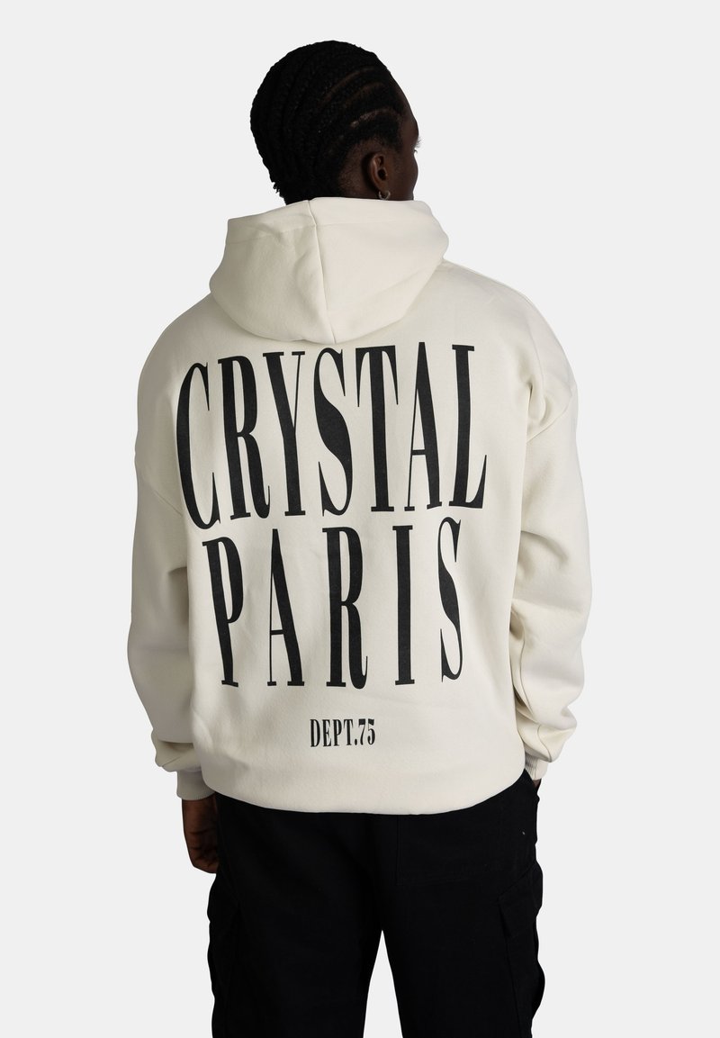 Felpa con cappuccio di colore crema, con grande stampa nera che riporta "CRYSTAL PARIS" e "DEPT.75" sul retro. Tessuto morbido, vestibilità rilassata, polsini a costine.