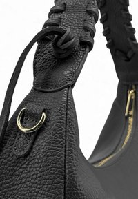 Sac à main en cuir noir avec une surface texturée, une poignée tressée et des accents de quincaillerie dorée près de l'ouverture zippée.