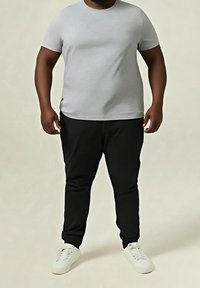 Camiseta gris de manga corta combinada con pantalones negros y zapatillas blancas. Diseño sencillo con cuello redondo y ajuste ceñido.