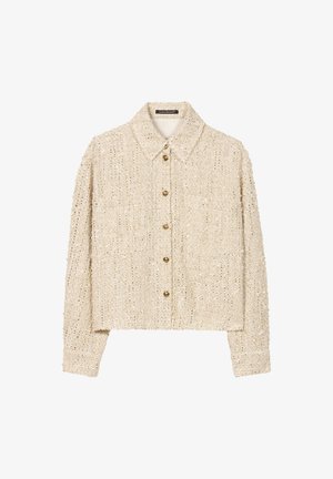 Beige textured cropped jacket with a collared neckline and front button closure, featuring two front pockets and golden buttons.