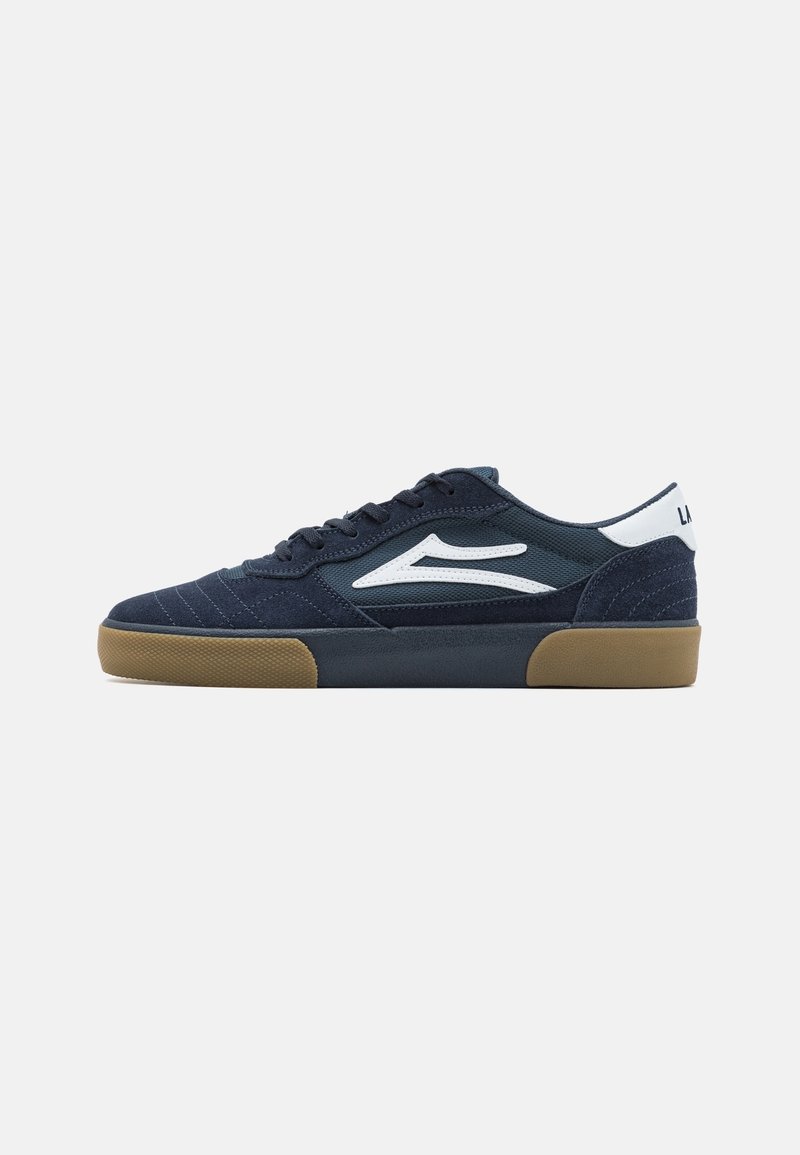 Marineblaue Sneakers aus strukturiertem Wildleder, mit weißem Seitenlogo, Gummisohle und kontrastierender Gummibasis. Schnürdesign mit gepolsterter Knöchelpartie.