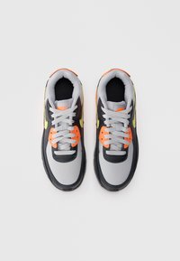 Nike tenisky v šedé, černé a neonově žluté barvě. Mezi vlastnosti patří texturovaný svršek, oranžové akcenty a tradiční šněrování.