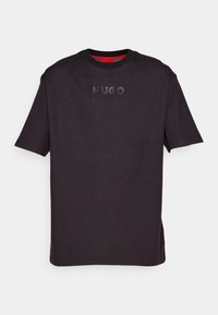 T-shirt noir à manches courtes en tissu texturé avec un logo "HUGO" en relief sur la poitrine et une bordure intérieure rouge au niveau de l'encolure.