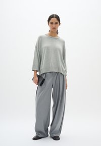 Light gray oversized knit sweater, wide gray plaid trousers, black clutch, and flat shoes. Simple, relaxed fit with dropped shoulders.