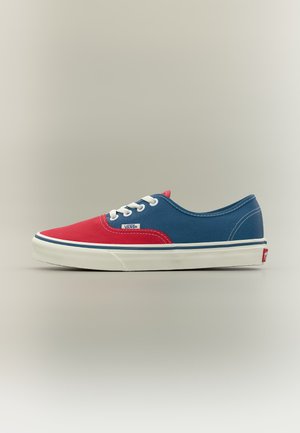 Zapatilla Vans de corte bajo con parte delantera roja, lados azules, cordones blancos y suela de goma blanca, mostrada de perfil sobre un fondo liso.
