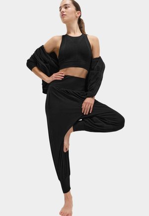 Sort sportstøj med en struktureret crop top og haremsbukser. Stoffet er glat, med en afslappet pasform og subtile draperingsdetaljer.
