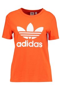 Kortärmad orange t-shirt i bomull med en vit Adidas-logotyp och tre horisontella ränder över logotypen, rund halsdesign.