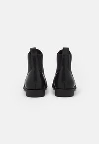 Svarta läderankelstövlar med elastiska sidopaneler, rund tå och låga blockklackar. Slät textur med minimala sömnadsdetaljer.