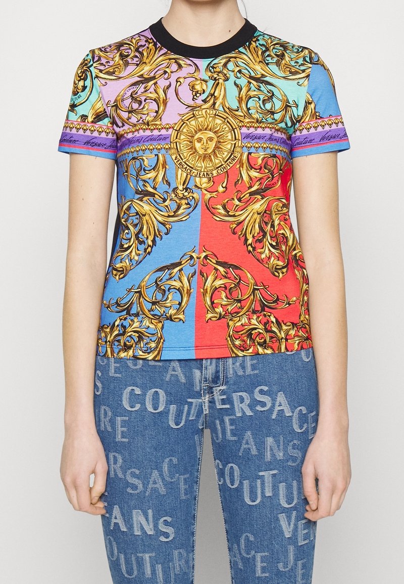 T-shirt colorato a maniche corte con intricati motivi dorati e un emblema solare su uno sfondo multicolore. Scollatura nera.