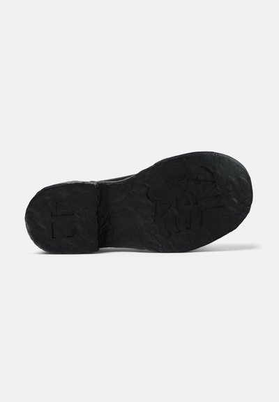 Black shoe sole, textured rubber with a rugged finish. Features embossed geometric patterns and a rounded toe design.