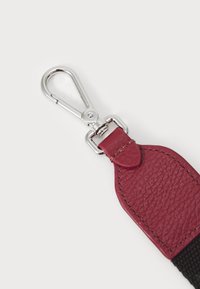 Red leather attachment with a textured finish, featuring a silver metal clip and loop, and black woven strap.