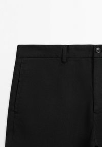 Pantaloni neri con tasca laterale, passante per cintura e chiusura con bottone, mostrati su sfondo bianco.
