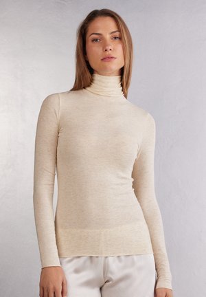 Beige långärmad polotröja i mjukt, texturerat tyg, med hög krage och en smal passform.
