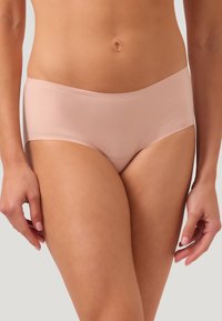 Ljusrosa, sömlösa hipsterunderkläder gjorda av ett slätt, elastiskt material. Har en midjehöjd som är något högre och en design med minimal täckning.
