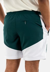 Calções de desporto masculinos com um tecido verde escuro e detalhes brancos, cintura elástica e um bolso traseiro com fecho de correr.