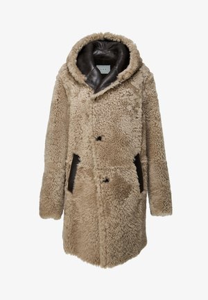 Beige keinonahkan takki, jossa on ruskea nahkakaulus, nappikiinnitys edessä ja sivutaskut, korostaen pörröistä tekstuuria.