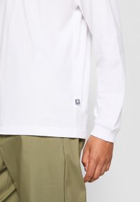 New Balance COURT LONG SLEEVE - Hosszú ujjú felső - white