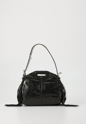 Black glossy leather handbag with a top handle and shoulder strap, featuring side tassels and a small cutout grip at the top center.