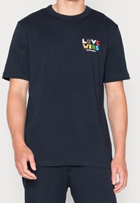 Tummansininen puuvillainen t-paita, jossa on lyhyet hihat ja pyöreä kaula-aukko. Vasemmalla rinnalla näkyvä "LOVE WINS" -monivärinen teksti.