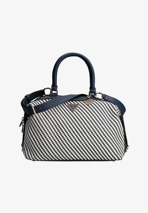 Bolso tejido en blanco y negro con asas y correa azul marino, con logo Guess en tonos dorados y un colgante en forma de corazón.