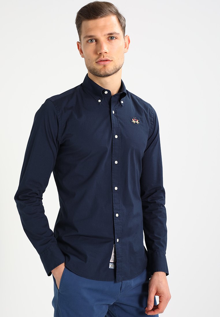 Navy blue long-sleeve button-down shirt made from smooth cotton, featuring a small embroidered design on the chest and button accents.