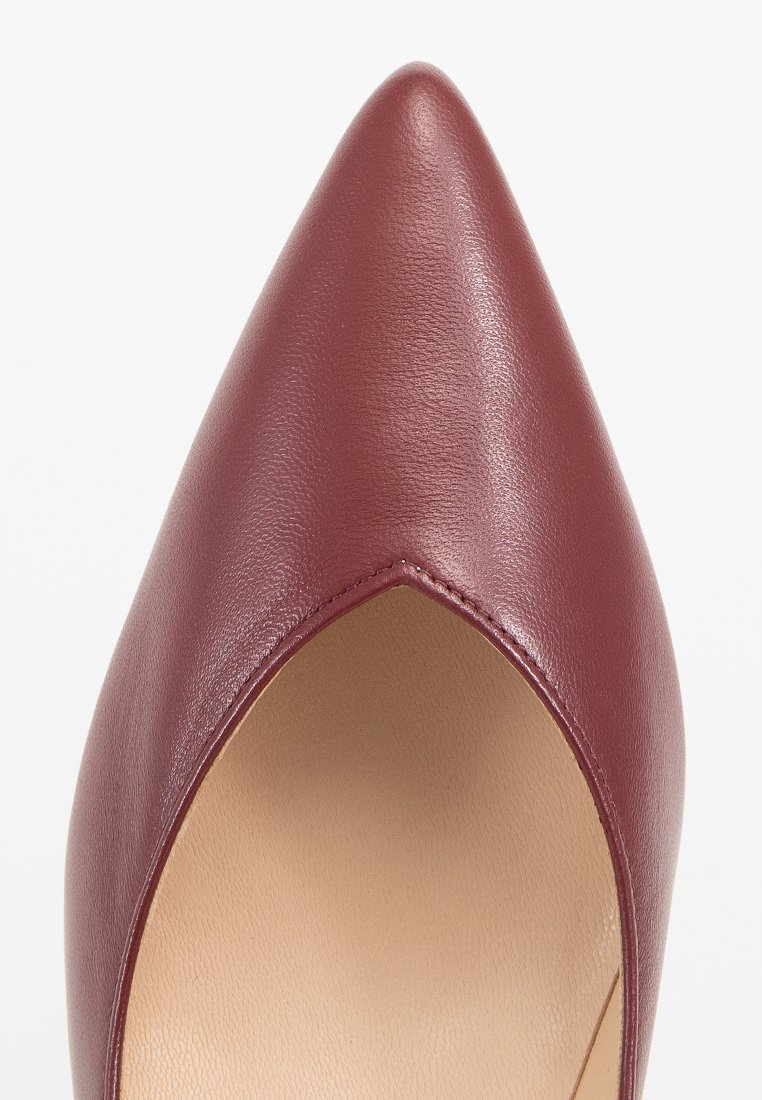 Scarpa in pelle bordeaux con punta affusolata, caratterizzata da una texture liscia e un bordo a V. L'interno presenta una fodera beige.