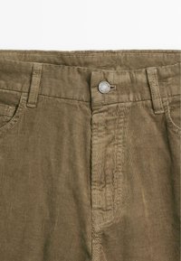 Khaki corduroybroek met een gestructureerd, ribbelig oppervlak. Voorzien van een metalen knoopsluiting, riemlussen en twee zijzakken.