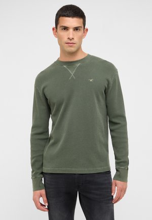 Hosszú ujjú, olíva zöld színű, wafelmintás kötött ing kerek nyakkivágással és finom keresztöltéses díszítéssel. Kis logó található a mellkasán.