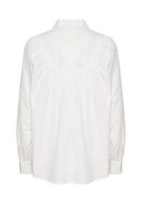 Bluză albă din bumbac, cu mâneci lungi, decolteu rotund și detalii de broderie delicate pe spate și pe manșete. Croială lejeră.