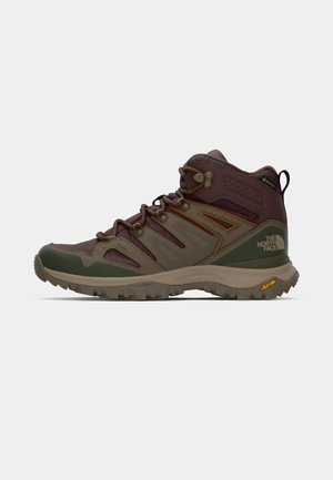 Rjavi in zeleni pohodni čevlji z mrežastimi paneli, gumijastim podplatom in podporo. Vključuje teksturirano površino in izstopajoči sistem vezalk.