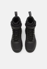 Black high-top sneakers with a textured fabric upper, padded ankle, laces, and adjustable strap. Rubber sole with a sleek design.